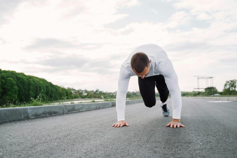 A man in sportswear begins his workout on an outdoor road, showcasing fitness and determination.