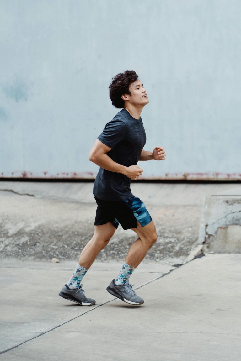 Energetic young man jogging outdoors focused on fitness and health in a casual urban setting.