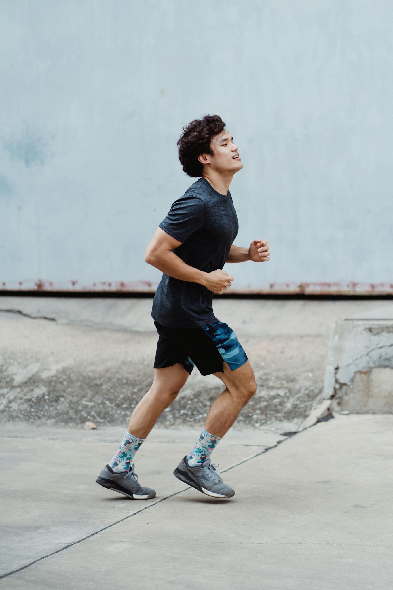 Energetic young man jogging outdoors focused on fitness and health in a casual urban setting.